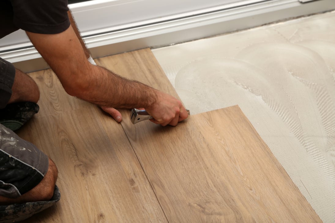 The worker installing new vinyl tile floor